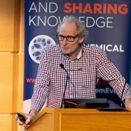 Main image of attendees asking questions from their seats with microphone. Secondary image is of group of attendees in a lecture hall clapping.