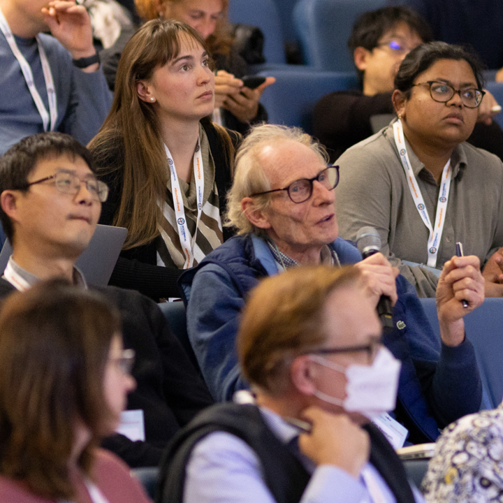 Main image of attendees asking questions from their seats with microphone. Secondary image is of group of attendees in a lecture hall clapping.