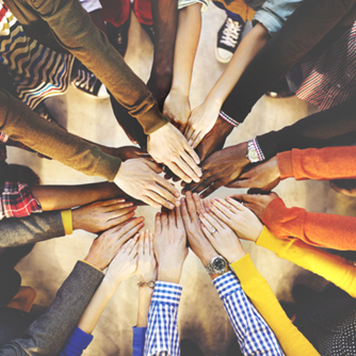 Photo of group of people working as a team with hands in the centre