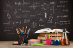 blackboard with science images with books and pencils in front