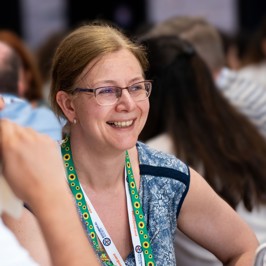Main image of female speaker in front of a wooden podium and Biochemical Society banner backdrop. Secondary image is of group of attendees networking among poster boards.