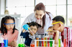 Female teacher showing three young children how to conduct a science experiment