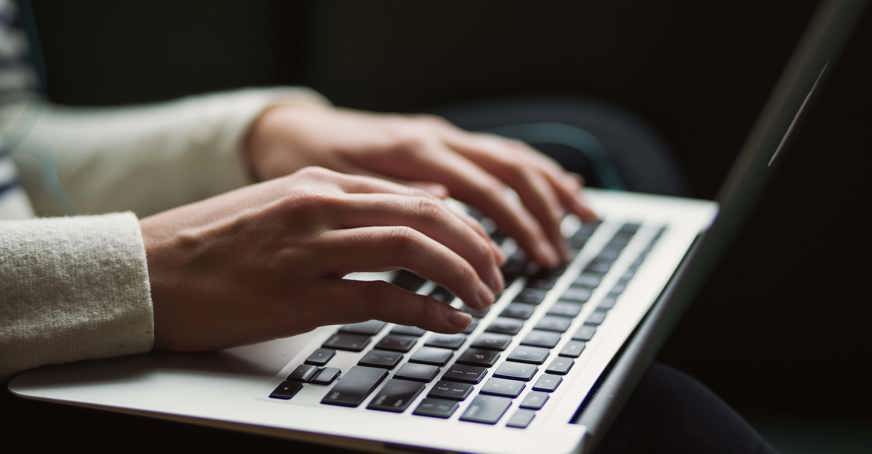 Hands typing on a laptop