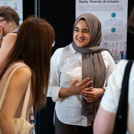 Main image is of two students discussing a scientific poster. Secondary image is of attendees networking during a poster session.