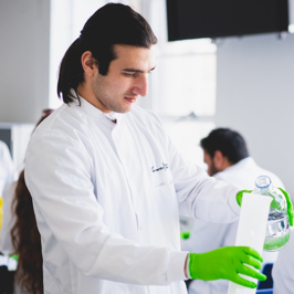 Main image of an undergraduate student registering attendance at a BIochemical Society event.  of group of attendees in a room with poster boards on display.