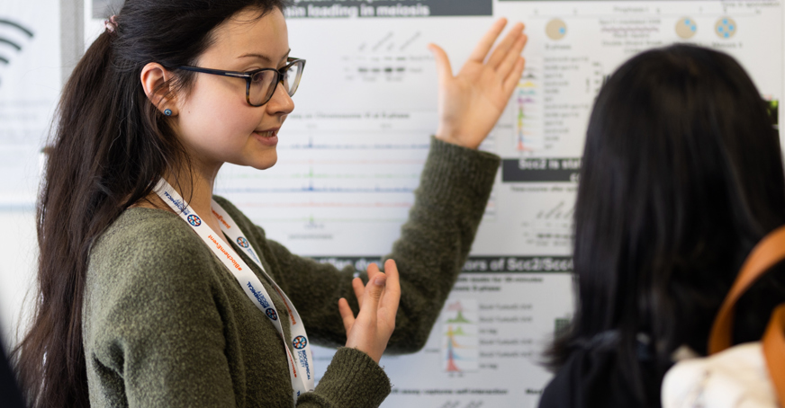 Early career, female scientists explaining her poster