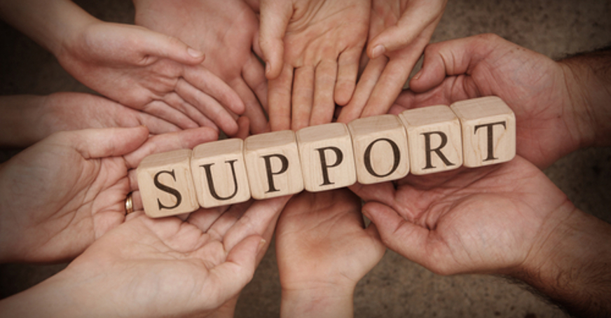 Group of hands holding wooden blocks spelling out support